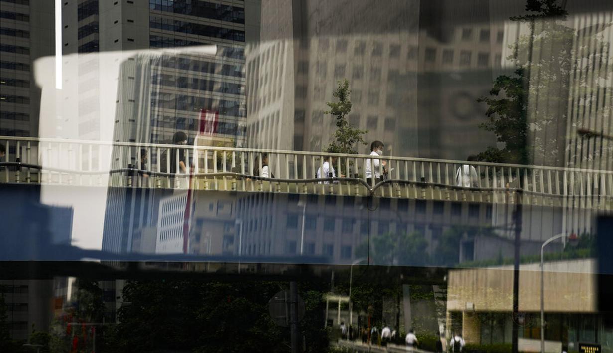 Komuter berjalan di jembatan menjelang Olimpiade 2020 di Tokyo, Jepang, Rabu (14/7/2021). Keadaan darurat akan berlaku sepanjang Olimpiade yang dibuka pada 23 Juli. (AP Photo/Jae C. Hong)