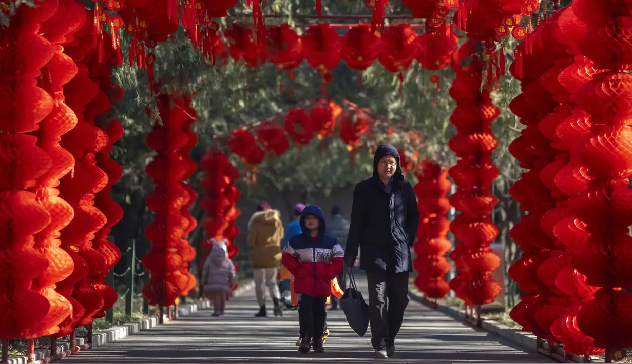 <p>Seorang pria dan anak laki-laki berjalan di sepanjang jalan yang dihiasi lentera untuk Tahun Baru Imlek mendatang di sebuah taman umum di Beijing, Jumat, 20 Januari 2023. Tahun Kelinci secara resmi dimulai pada 22 Januari. (AP Photo/Mark Schiefelbein)</p>