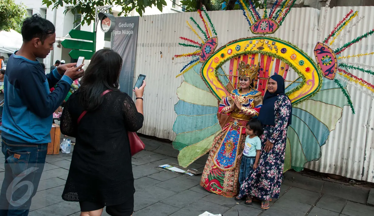 Warga berpose dengan seniman yang mencari nafkah di kawasan Kota Tua, Jakarta, Senin (5/1). Kota Tua masih menjadi tempat pilihan untuk warga Jakarta dan sekitarnya mengisi waktu libur. (Liputan6.com/Gempur M Surya)
