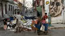 Warga Kuba mengumpulkan bahan mentah dari sejumlah besar sampah di sebuah jalan di Havana pada 23 Agustus 2024. (YAMIL LAGE / AFP)