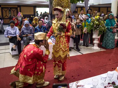 Pasangan pengantin saat mengikuti nikah massal di Surabaya, Jawa Timur, Rabu (18/12/2019). Sebanyak 60 pasangan pengantin mengikuti nikah massal yang digelar Dinas Sosial Kota Surabaya. (JUNI KRISWANTO/AFP)