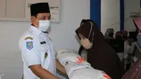 Plt Wali Kota Bengkulu Dedy Wahyudi menyerahkan bantuan beras dari Kementrian Sosial melalui program keluarga harapan. (Liputan6.com/Yuliardi Hardjo)
