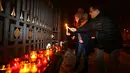 Warga di kedutaan Rusia di Minsk, Belarus menyalakan lilin sebagai ungkapan berkabung atas tragedi jatuhnya pesawat militer Rusia Tupolev Tu-154 di Laut Hitam, Rusia, Minggu (25/12). (REUTERS / Vasily Fedosenko)