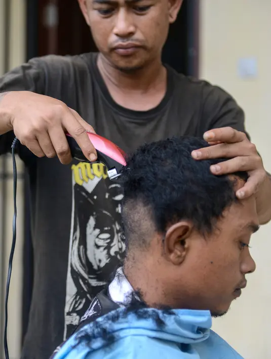 Seorang anak Punk dicukur rambutnya di Banda Aceh (9/1). Provinsi Aceh menjadi salah satu daerah di Indonesia yang menerapkan hukum Syariah bagi masyarakatnya. (AFP Photo/Chaideer Mahyuddin)