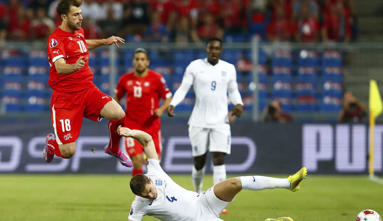 Pemain depan Timnas Swiss, Admir Mehmedi (kiri), melompat menghindari tackling gelandang Inggris, Jordan Henderson, di laga kualifikasi Euro 2016 di Stadion St Jakob-Park, Basel , (9/9/2014). (REUTERS/Ruben Sprich)