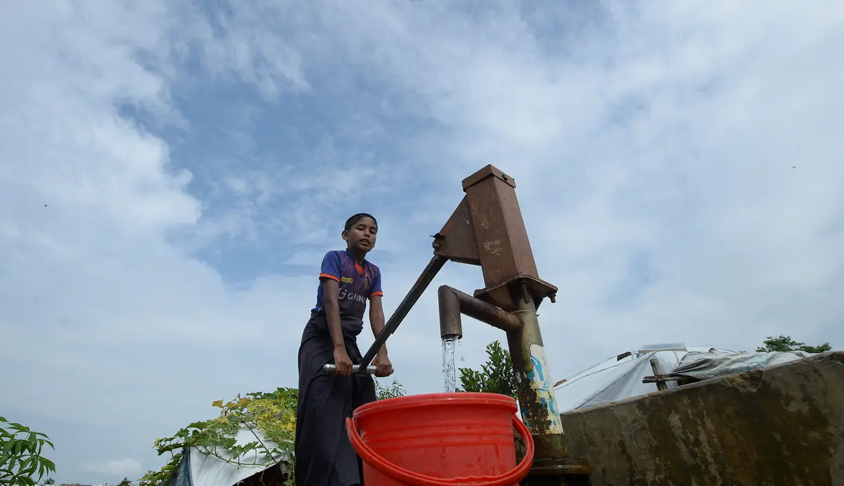 Seorang pemuda Rohingya mengumpulkan air minum dari sumur di kamp Kutupalong, di Ukhia, Bangladesh pada 6 Oktober 2020. Lebih dari satu juta etnis Rohingya melarikan diri dari Myanmar dan menetap di Kutupalong yang merupakan salah satu kamp pengungsi terbesar di dunia. (Munir Uz Zaman/AFP)