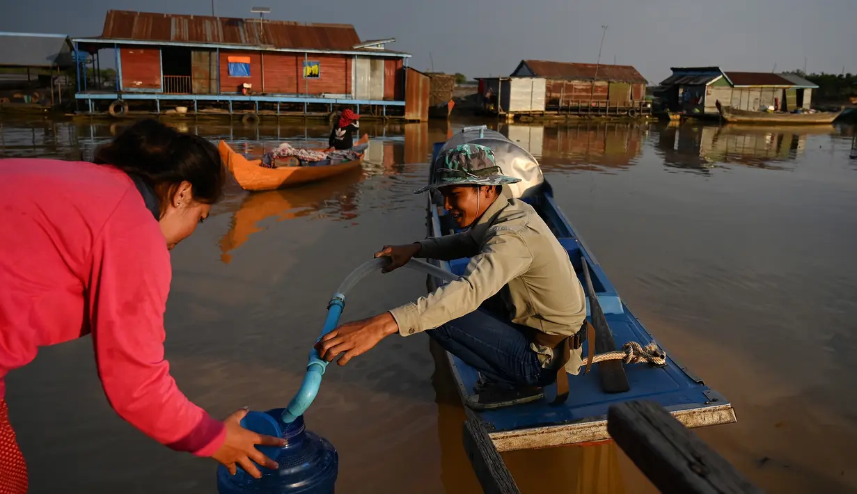 Seorang wanita mengisi sebuah wadah dengan air di sebuah desa terapung di sepanjang sungai Siem Reap, Kamboja (5/12/2019). Sungai ini merupakan titik awal yang ideal untuk kunjungan ke desa-desa terapung tradisional Kamboja. (AFP/Manan Vatsyayana)
