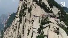 Sejumlah pekerja bertaruh nyawa di ketinggian 7000 kaki untuk mengganti papan kayu usang di sepanjang jembatan Gunung Huashan. Ini dalam rangka menyambut wisatawan di musim panas.