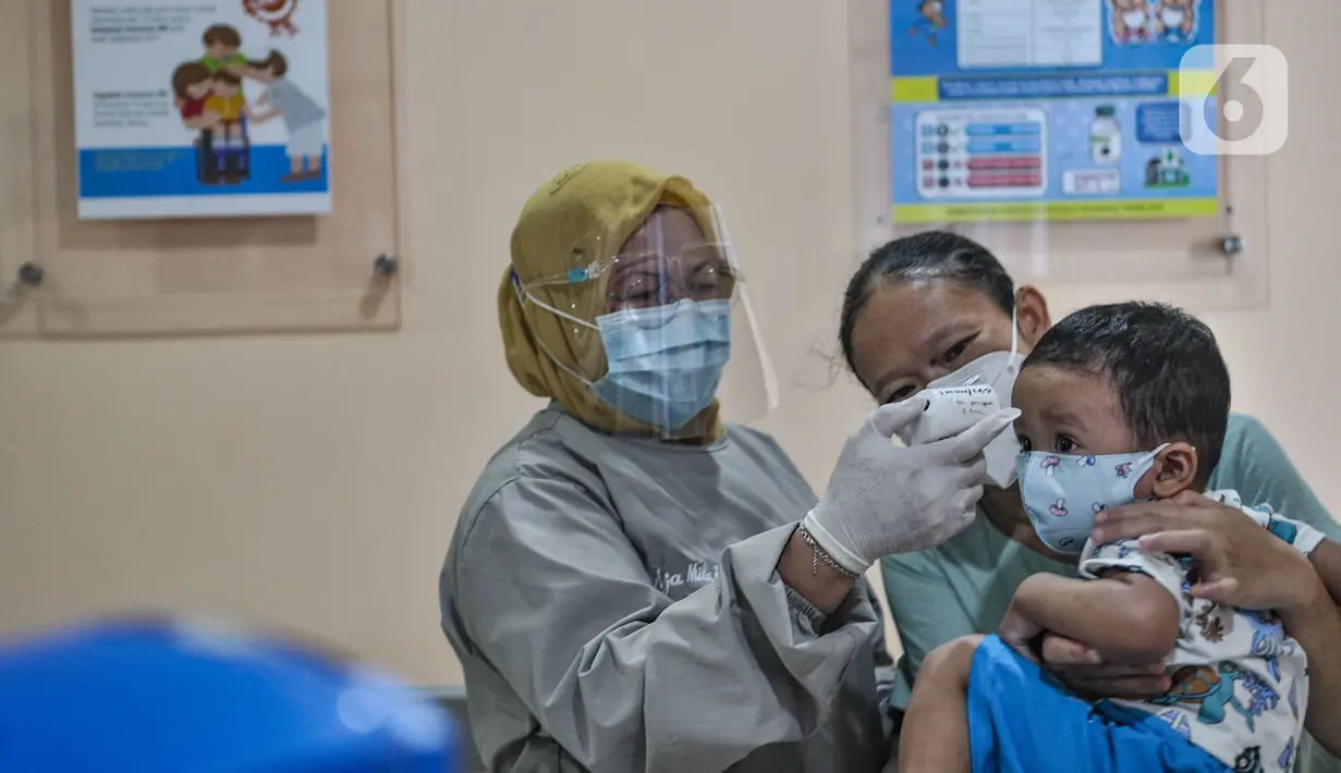 Dokter memeriksa suhu tubu balita sebelum mengikuti imunisasi di Puskesmas Kecamatan Jatinegara, Jakarta, Kamis (26/11/2020). Kegiatan imunisasi menerapkan protokol 3M, baik bagi dokter, sang ibu, maupun balita agar program Menuju Indonesia Sehat dapat tercapai. (merdeka.com/Iqbal S. Nugroho)