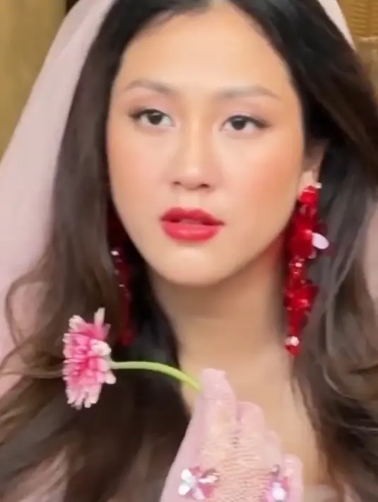 Sherina juga mengenakan veil pink di atas rambut coklat terurai bak pengantin. Sambil memegang bunga, tampak ia juga mengenakan glove jaring pink dengan aksen beads senada seperti gaunnya.  [@vagueskin]