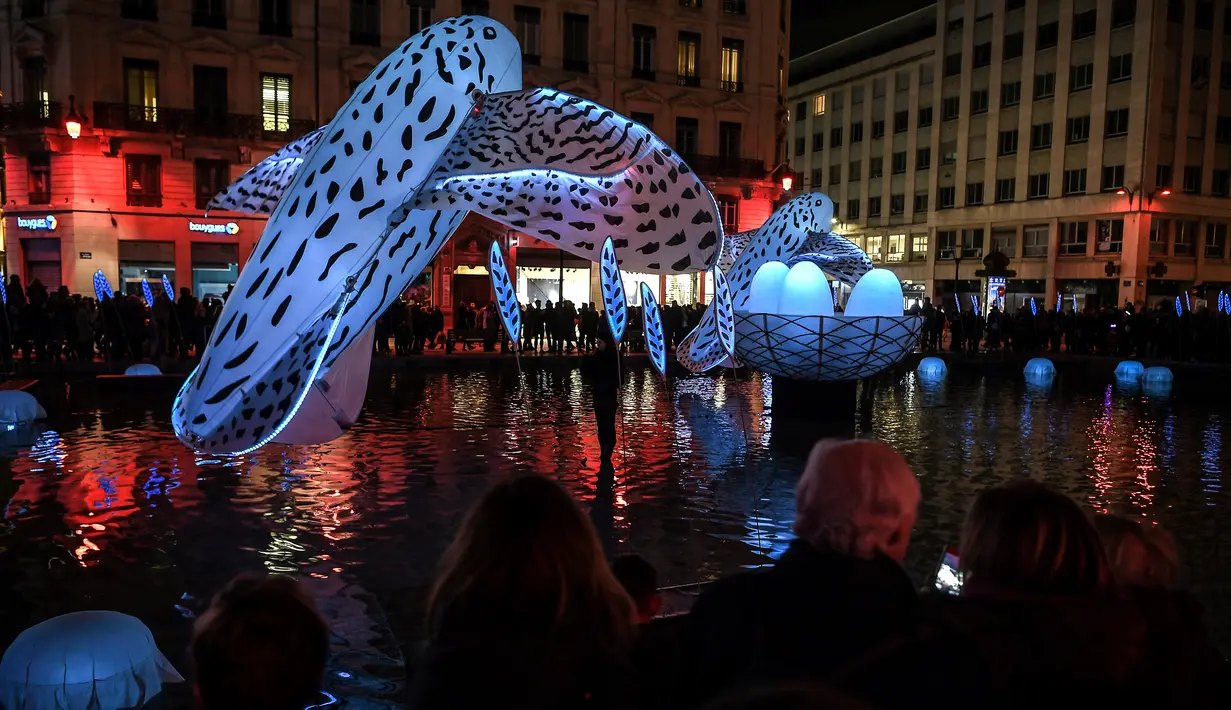 Orang-orang melihat instalasi seni yang diterangi cahaya dalam festival cahaya Fete des Lumieres di Lyon, Prancis, 7 Desember 2017. Selama festival, berbagai sudut Kota Lyon menjadi benderang dengan cahaya unik dan kreatif. (AFP PHOTO / PHILIPPE DESMAZES)