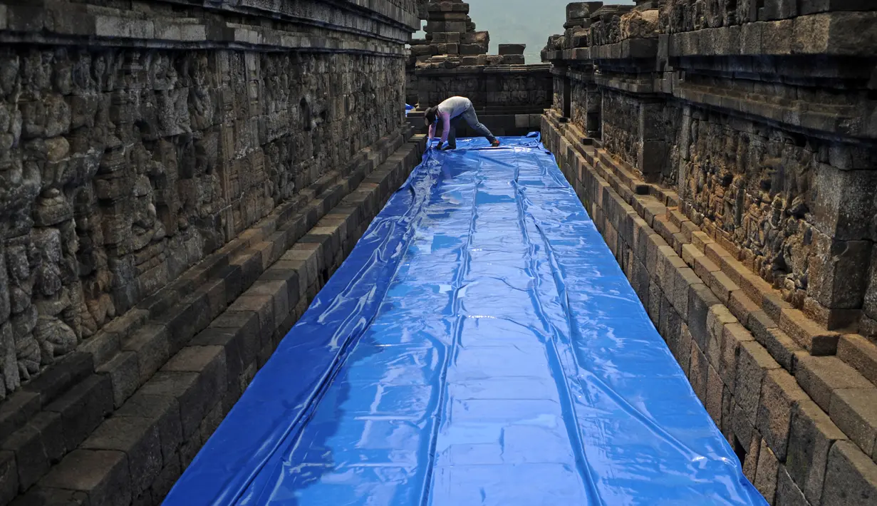 Seorang pekerja melapisi lantai di kompleks candi Borobudur, Magelang, Jawa Tengah, Senin (23/11/2020). Penutupan candi Borobudur oleh BKB (Balai Konservasi Borobudur) sebagai langkah antisipasi melindungi batu candi dari abu vulkanik jika Gunung Merapi erupsi. (Photo by Agung Supriyanto / AFP)