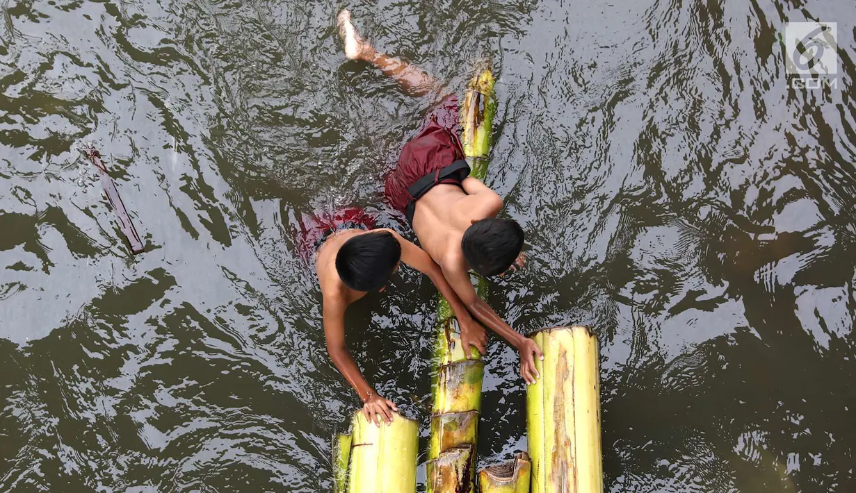 Anak-anak berenang menggunakan batang pohon pisang di bantaran Sungai Ciliwung, Jakarta, Selasa (15/5). Aktivitas tersebut berbahaya bagi kesehatan dan keselamatan mereka. (Liputan6.com/Immanuel Antonius)