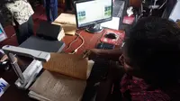 Petugas sedang melakukan digitalisasi naskah kuno dengan memindai untuk dipindahkan ke komputer d Reksa Pustaka.(Liputan6.com/Fajar Abrori)