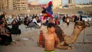 Mohammed al Sheikh ketika meliukkan tubuhnya di atas unta di sebuah pantai Kota Gaza, Palestina, Kamis (2/6). Dengan tinggi badan 1,6 meter dan berat mencapai 29 kg, Mohammed mampu menekukan tubuhnya dengan berbagai posisi. (REUTERS/Mohammed Salem)