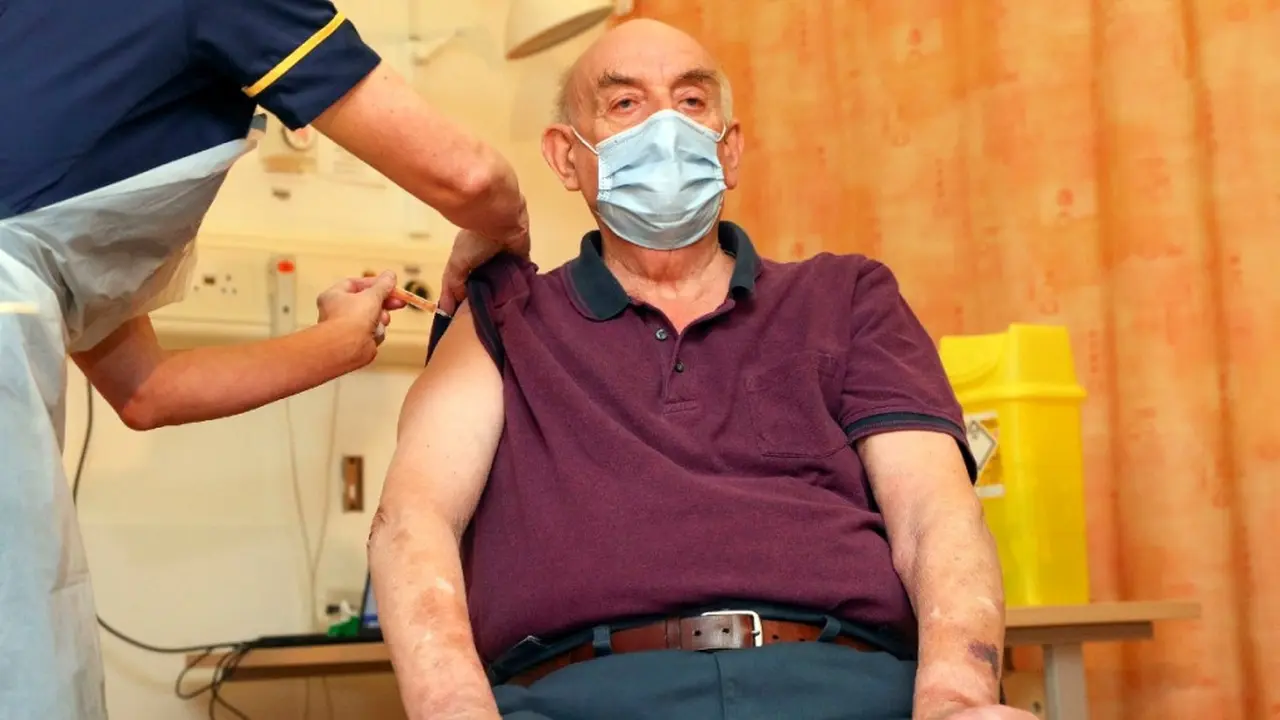 Brian Pinker yang berusia 82 tahun, orang pertama di dunia penerima vaksin COVID-19 Universitas Oxford/AstraZeneca dari perawat Sam Foster di Rumah Sakit Churchill di Oxford, Inggris, pada 4 Januari 2021. (Steve Parsons / Pool Photo via AP)