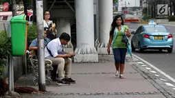 Seorang wanita melintasi trotoar di kawasan MH Thamrin, Jakarta, Selasa (6/3). Dalam perencanaan penataan jalan dan trotoar di wilayah Sudirman-Thamrin, Gubernur DKI memberikan jalur untuk sepeda motor agar dapat melintas. (Liputan6.com/Immanuel Antonius)