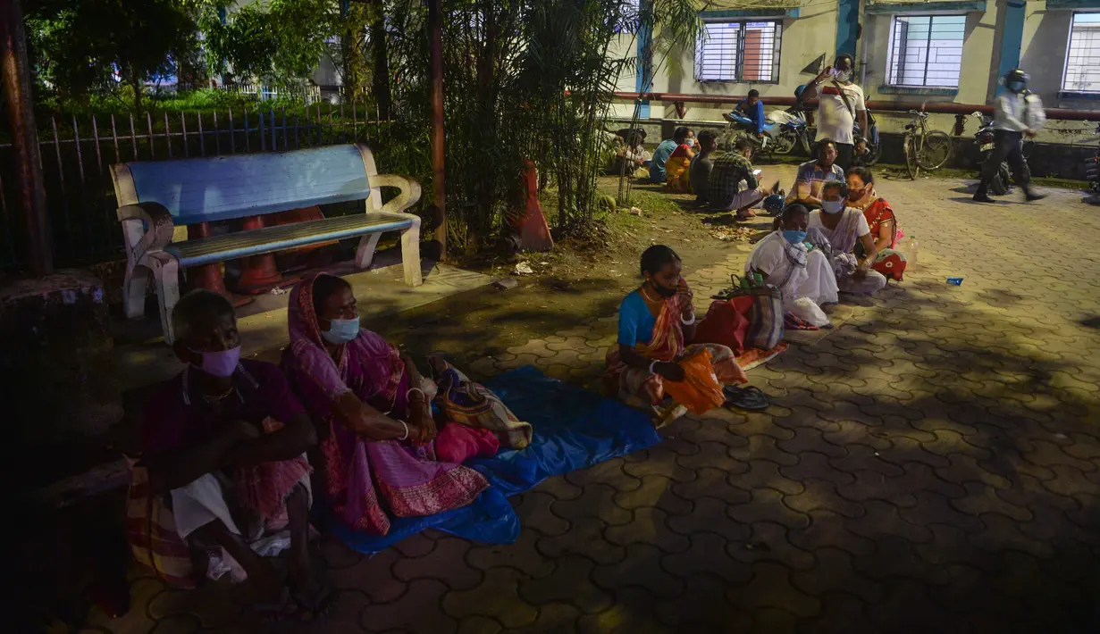 Orang-orang berkemah semalam untuk mendapatkan vaksin Covid-19 pada hari berikutnya di rumah sakit distrik yang dikelola pemerintah di Siliguri, negara bagian Bengal Barat, India, Senin (20/9/2021). Hingga 19 September 2021, sebanyak 202 juta orang India telah divaksin dua dosis (Diptendu DUTTA/AFP)