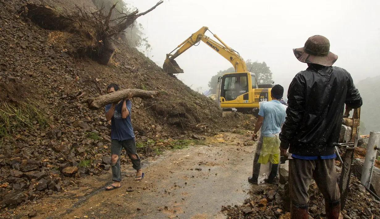 Alat berat diturunkan untuk memperbaiki jalan yang terkena longsor di Tuba, Filipina (6/7/2015). Akibat badai aktivitas penerbangan, pelabuhan dan sekolah-sekolah ditutup. (REUTERS/Harley Palangchiao)