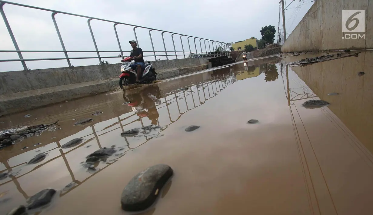 Pengendara motor melintasi genangan air di kawasan Kemiri Muka, Depok, Jawa Barat, Senin (2/10). Buruknya sistem drainase menyebabkan air selalu menggenang setiap musim hujan sehingga mengganggu aktivitas warga. (Liputan6.com/Immanuel Antonius)