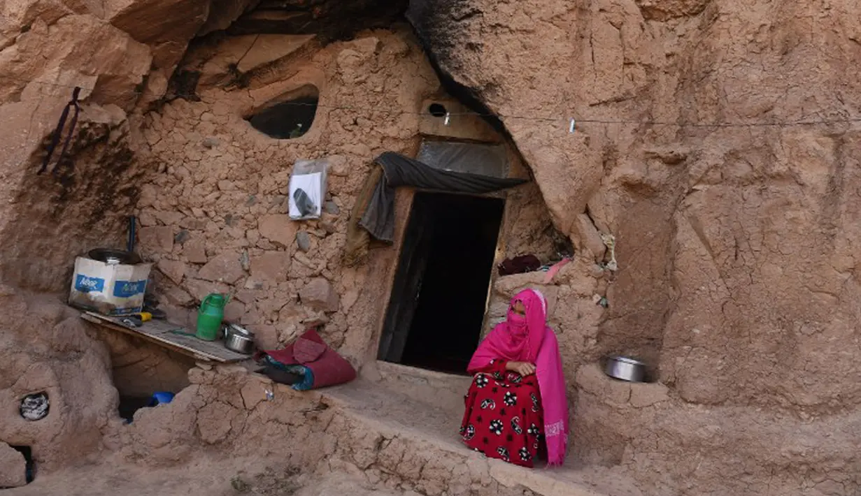 Seorang wanita duduk di pintu masuk gua di kota Bamiyan, Kabul. Foto diambil pada 19 Juni 2015. Ratusan warga miskin Afghanistan terpaksa menghuni gua-gua tersebut untuk dijadikan rumah karena tak memiliki tempat tinggal. (AFP PHOTO / SHAH Marai)