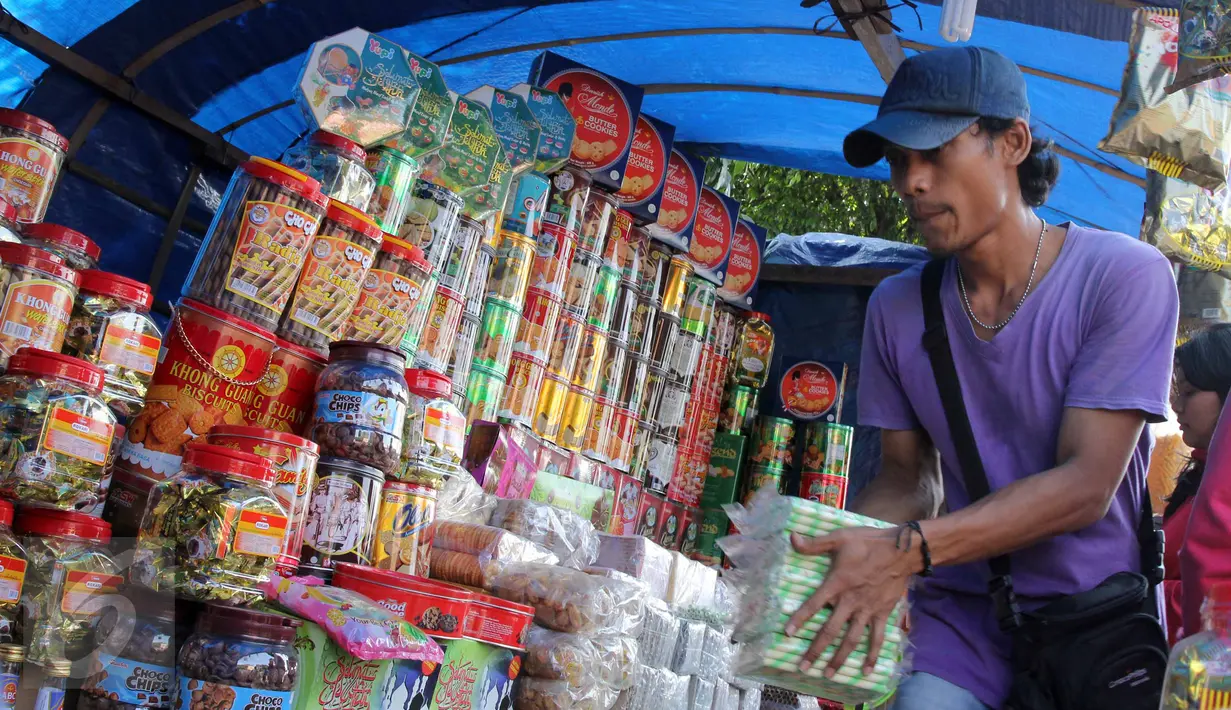 Pedagang menata kue kaleng di kios penjual kue kering musiman di kawasan Ciracas, Jakarta, Minggu (12/7). Sejak beberapa hari terakhir, transaksi pedagang musiman kue kering mengalami peningkatan jelang hari raya Idul Fitri. (Liputan6.com/Helmi Afandi)