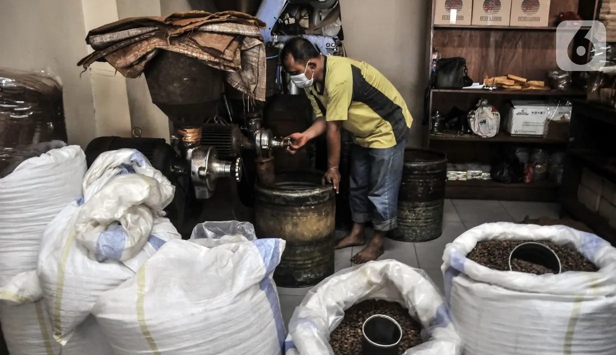 Pekerja menggiling biji kopi di toko kopi Sari Murni, Jatinegara, Jakarta Timur, Selasa (4/1/2021). Pengelola toko, Rudi mengungkapkan proses pengolahan kopi masih dengan cara tradisional. (merdeka.com/Iqbal S. Nugroho)
