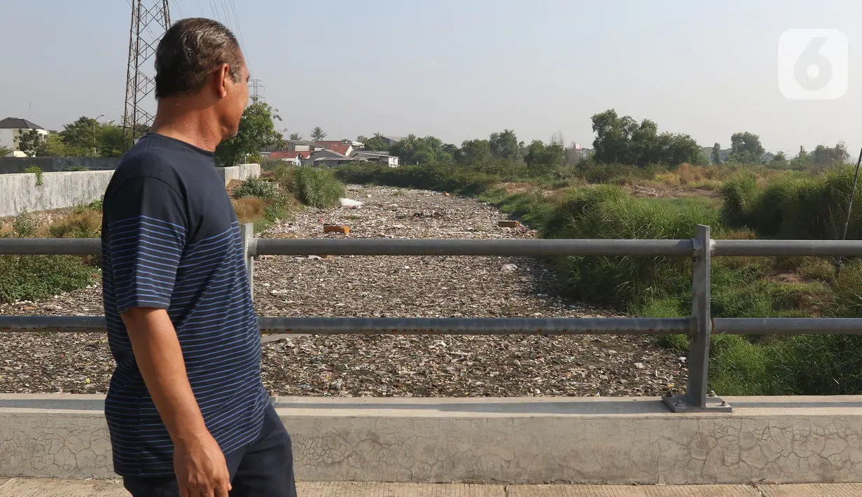 Seorang warga mengamati sampah menumpuk di aliran kali Kampung Bogor, Desa Setiasih, Tarumajaya, Kabupaten Bekasi, Rabu (30/9/2020). Tumpukan sampah yang didominasi oleh sampah plastik dan Styrofoam tersebut membentang sekitar 200 meter di aliran kali Kampung Bogor. (Liputan6.com/Herman Zakharia)