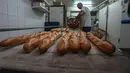 Baker David Buelens memasukkan baguette ke dalam keranjang di sebuah toko roti, di Versailles, sebelah barat Paris, Selasa, 29 November 2022. Roti, yang disebut Presiden Prancis Emmanuel Macron sebagai "250 gram keajaiban dan kesempurnaan," telah jadi bagian klasik kehidupan warga negara itu. (AP Photo/Michel Euler)