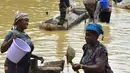 Para penambang emas wanita bekerja di sungai Pampana di dekat Mekeni, sebelah utara Sierra Leone (5/3). Melintasi tanah yang curam, ratusan pria dan wanita di sungai menyaring kerikil, memisahkan bintik-bintik emas dari lumpur. (AFP Photo/Issouf Sanogo)