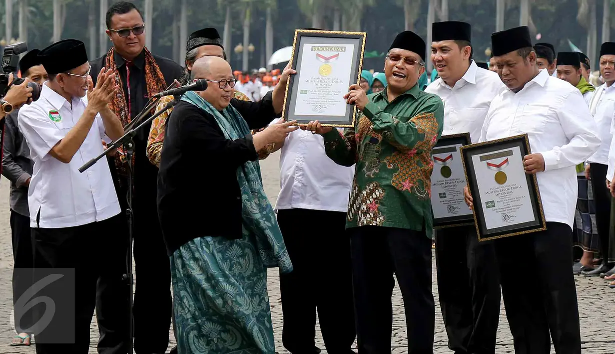 Ketua MURI Jaya Suprana memberikan piagam untuk pembacaan serentak 1 miliar shalawat Nariyah dan kirab terjauh kepada Ketum PBNU Said Aqil Siradj dalam Hari Santri Nasional di Monas, Jakarta, Sabtu (22/10). (Liputan6.com/Fery Pradolo)