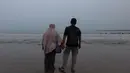 Yanti, istri jurnalis foto Merdeka.com Arie Basuki, bersama putranya Bintang berdiri menatap perairan Selat Sunda sambil memanjatkan doa dalam prosesi tabur bunga di pantai dekat Dermaga Pegedongan, Banten, Jumat (18/9/2026). Doa tersebut dipanjatkan sebagai bentuk harapan agar Arie Basuki dan tujuh penumpang Arupadhatu 1 lainnya segera ditemukan. (KLY/Budy Santoso)