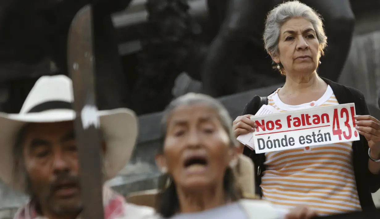 Demonstran membawa selembaran selama pawai peringatan 14 bulan hilangnya mahasiswa Universitas Ayotzinapa Raul Isidro Burgos di Meksiko, (26/11). Mereka menuntut Presiden Meksiko memberi kejelasan atas nasib 43 siswa yang hilang. (REUTERS/Daniel Becerril)