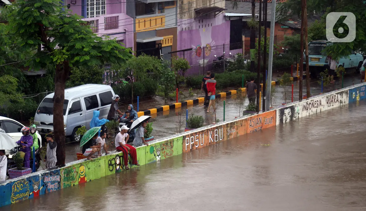 Warga melihat-lihat kondisi Banjir Kanal Barat di Kawasan Tanah Abang, Jakarta, Rabu (1/1/2020). Hujan yang mengguyur Jakarta sejak Selasa sore (31/12/2019) mengakibatkan debit air Banjir Kanal Barat tinggi dan hampir meluap. (Liputan6.com/Helmi Fithriansyah)