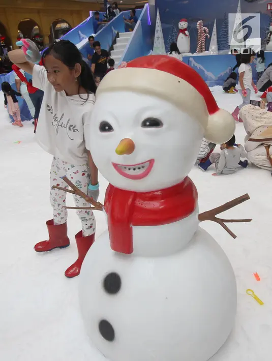 Seorang anak berpose disamping boneka es di Snow Village di salah satu pusat perbelanjaan di kawasan Tangsel, Senin (17/12). Jelang Natal dan Tahun Baru sejumlah pusat perbelanjaan menyajikan kegiatan untuk menarik pengunjung. (Merdeka.com/Arie Basuki)