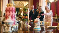 Ratu Inggris Elizabeth II melihat penataan makanan penutup yang biasa dimakan Ratu Victoria sebagai bagian dari pameran di Istana Buckingham, London, Rabu (17/7/2019). Pameran yang dibuka pada 20 Juli ini menandai peringatan 200 tahun kelahiran Ratu Victoria. (Victoria Jones/POOL/AFP)