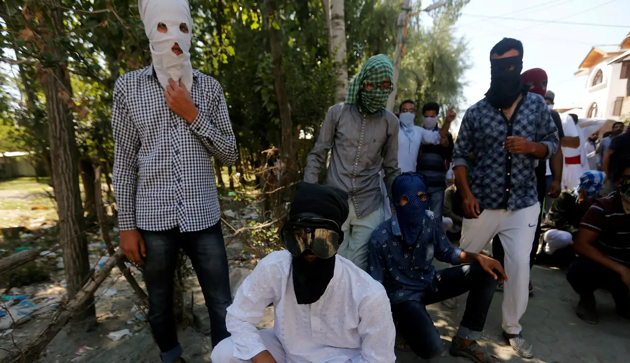 Pengunjuk rasa mengenakan penutup wajah jelang melakukan aksi protes terhadap pembunuhan yang terjadi baru-baru ini di Kashmir, Jumat (5/8). (REUTERS / Danish Ismail)