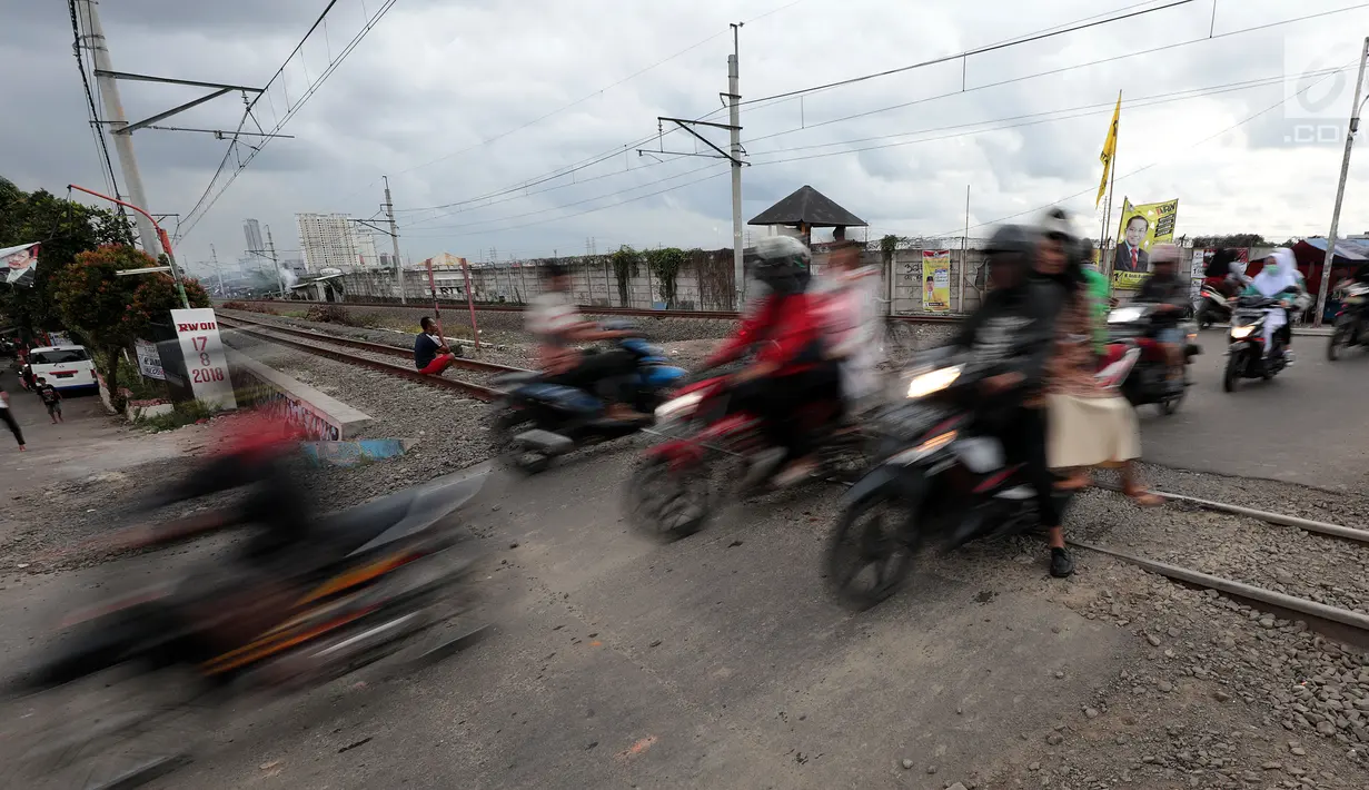 Pengendara motor melewati perlintasan kereta api tanpa palang pintu di kawasan Kelingkit, Rawa Buaya, Jakarta, Selasa (26/2). Rel kereta tanpa adanya palang pintu penutup ini sangat berbahaya karena bisa menyebabkan kecelakaan. (Liputan6.com/Johan Tallo)