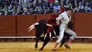 Matador asal Peru, Andres Roca Rey berusaha menghindar dari serudukan banteng di arena adu banteng Real Maestranza di Sevilla, Spanyol (21/4). (AFP Photo/Cristina Quicler)