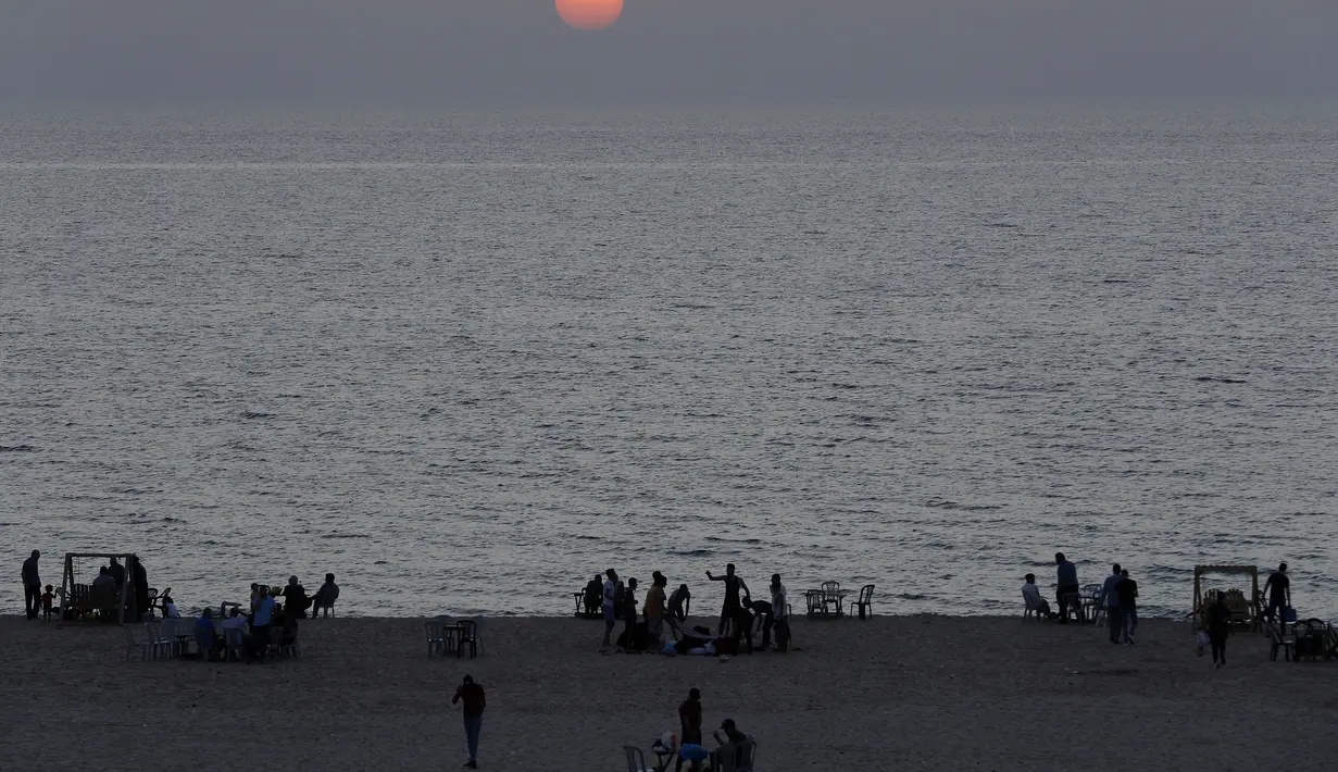 Para anggota keluarga menunggu waktu berbuka puasa saat bulan suci Ramadan di pantai Kota Gaza, Palestina, Kamis (21/5/2020). Di tengah pandemi COVID-19, berbuka puasa bersama di pantai Kota Gaza tetap ramai. (AP Photo/Adel Hana)