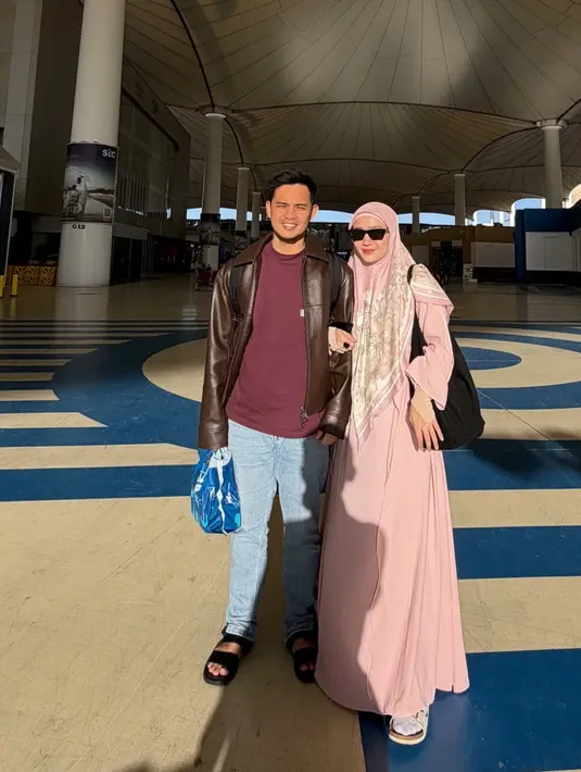 Febby Rastanty tampak menjalankan umrah di bulan Ramadan bersama suaminya. Febby mengenakan abaya pink senada dengan kerudung panjang pink bermotif.  [@febbyrastanty]