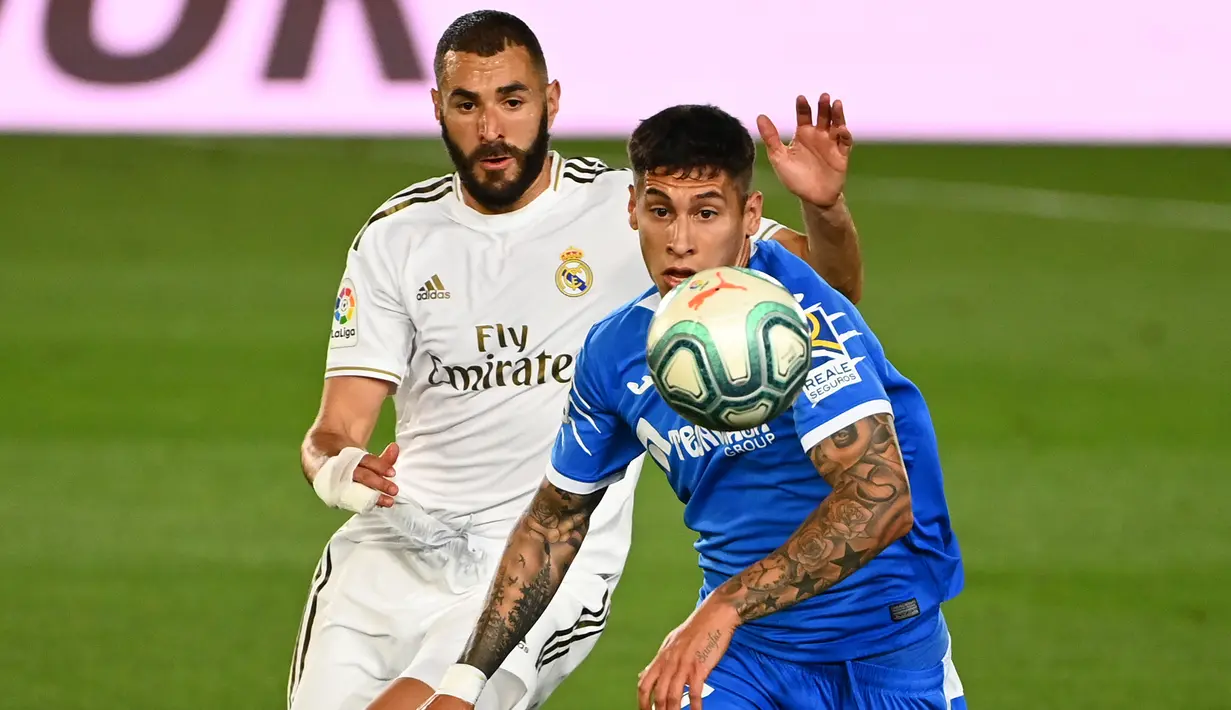 Penyerang Real Madrid, Karim Benzema, berebut bola dengan bek Getafe, Mathias Olivera, pada laga lanjutan La Liga pekan ke-33 di Stadion Alfredo Di Stefano, Jumat (3/7/2020) dini hari WIB. Real Madrid menang 1-0 atas Getafe. (AFP/Gabriel Bouys)