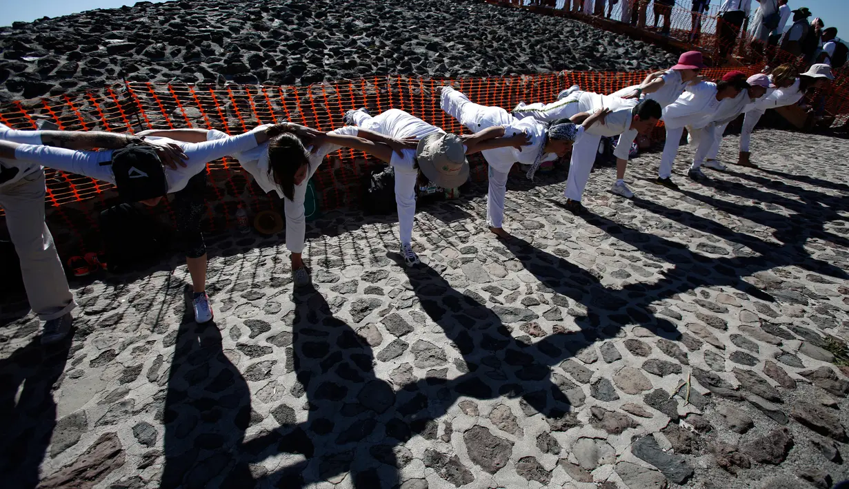 Sekelompok orang melakukan gerakan yoga diatas Piramida Matahari saat merayakan equinox musim semi di situs arkeologi Teotihuacan, Meksiko (21/3). Ritual itu diikuti oleh ribuan pengunjung yang naik ke piramida kuno. (AP Photo/Rebecca Blackwell)