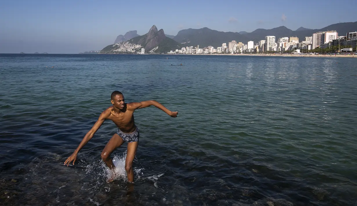 Seorang pria berjalan di daerah berbatu di pantai Arpoador selama gelombang panas di Rio de Janeiro, Brasil, pada hari libur kota Saint Sebastian, Kamis (20/1/2022). (AP Photo/Bruna Prado)