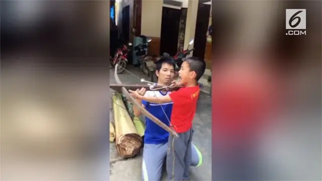 Seorang bocah di Vietnam menggunakan sebuah busur panah untuk mencopot gigi.