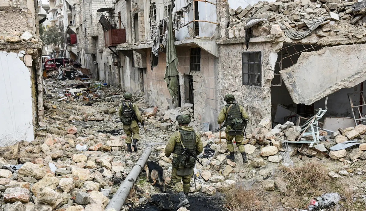 Para tentara Rusia berjalan di tengah bangunan yang rusak saat melakukan patroli dalam operasi APCs di Aleppo, Suriah. (Russian Defense Ministry Press Service photo via AP)
