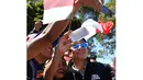 Dengan membawa bendera Merah-Putih fans dari Indonesia berebut foto saat bertemu Rio Haryanto  sebelum balapan perdana Formula One Australian Grand Prix, Melbourne, Minggu (20/3/2016). (AFP/Paul Crock)