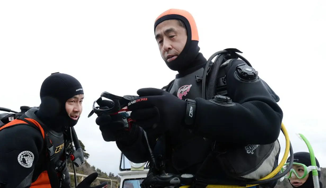 Yasuo Takamatsu (kanan) mendengarkan arahan instruktur selam di perairan laut yang dingin di Onagawa Miyagi Jepang (2/03/2014) (AFP Photo/Toru Yamanaka).