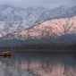 Orang-orang menikmati perjalanan dengan perahu dengan latar belakang pegunungan yang tertutup salju di danau Dal di Srinagar (11/1/2022). Danau Dal yang merupakan danau terbesar kedua di propinsi Jammu dan Kashmir negara bagian India ini merupakan pusat pariwisata dan rekreasi. (AFP/Tauseef Mustafa)