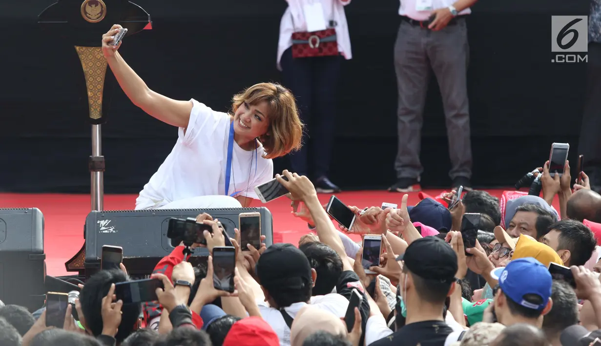 Aktris, Nirina Zubir berswafoto bersama warga jelang peresmian pengoperasian Moda Raya Terpadu Jakarta fase 1 di Kawasan Bundaran HI, Jakarta, Minggu (24/3). Peresmian dilakukan oleh Presiden Joko Widodo, Gubernur DKI Jakarta, Anies Baswedan serta pihak terkait. (Liputan6.com/Helmi Fithriansyah)